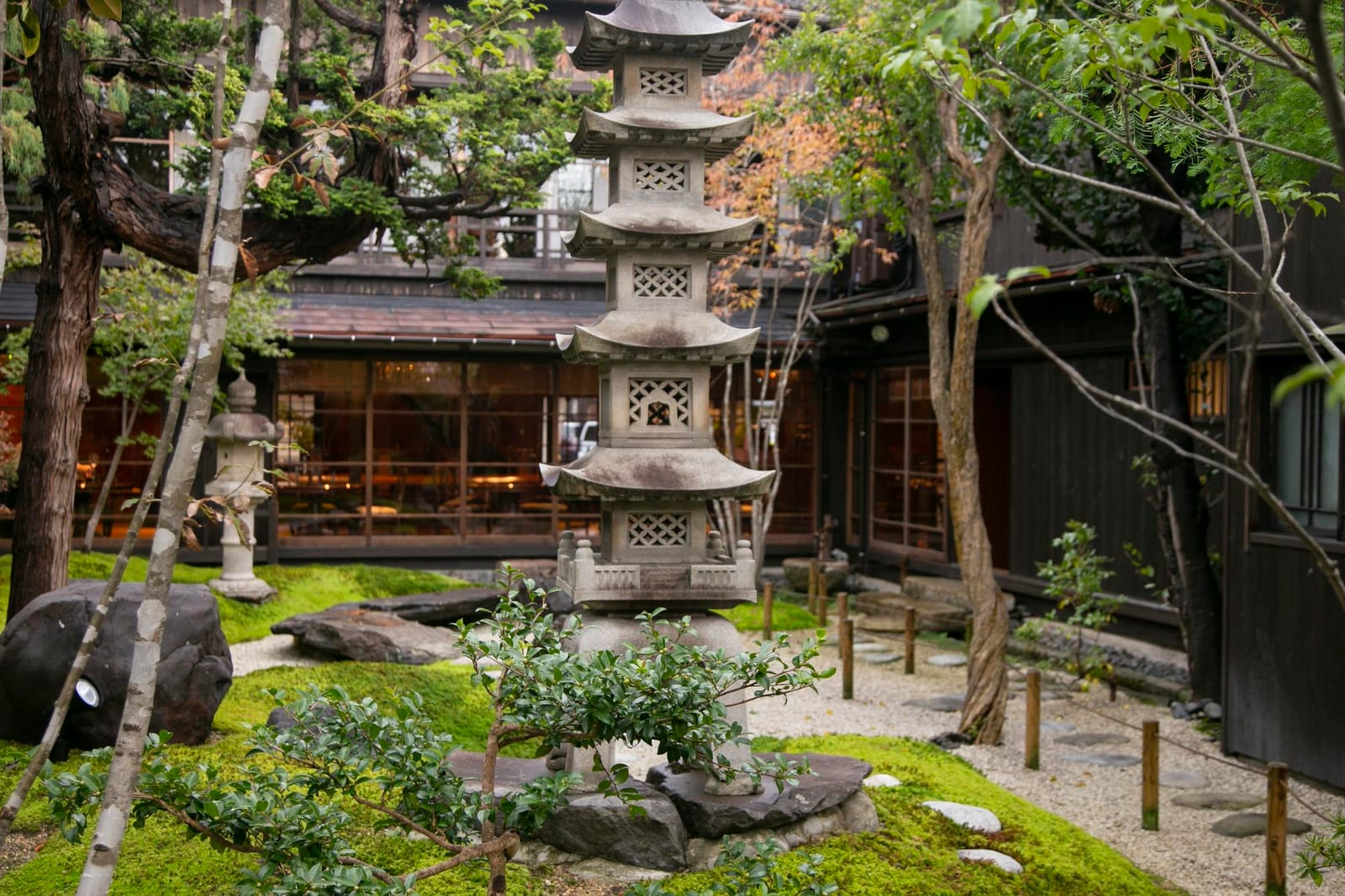 木造の別荘のそばにある苔むした日本庭園の石灯籠